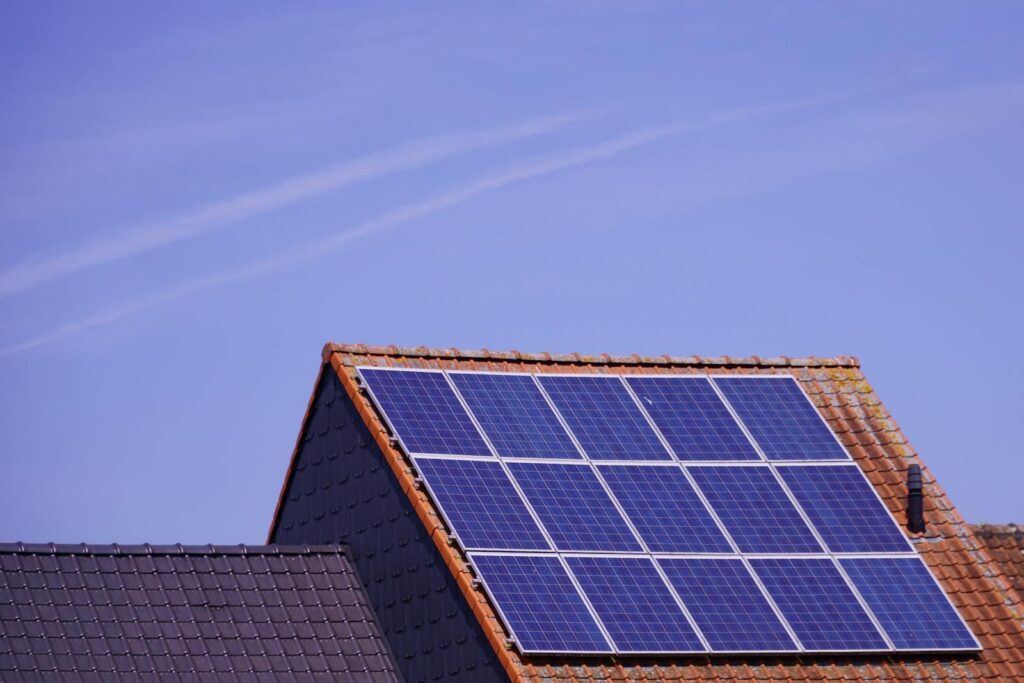 Close-up of solar panels on a tiled rooftop under a clear sky, showcasing renewable energy.