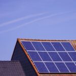 Close-up of solar panels on a tiled rooftop under a clear sky, showcasing renewable energy.