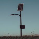 A solar-powered street light stands tall against a clear blue sky, symbolizing renewable energy.